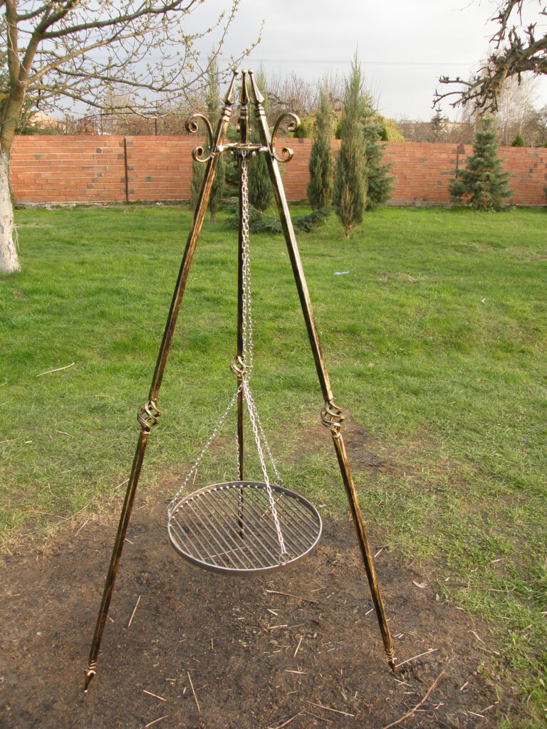 Stylowy grill z trzema nogami, regulacja wysokości, ręczna patyna w złocie, solidny profil metalowy.