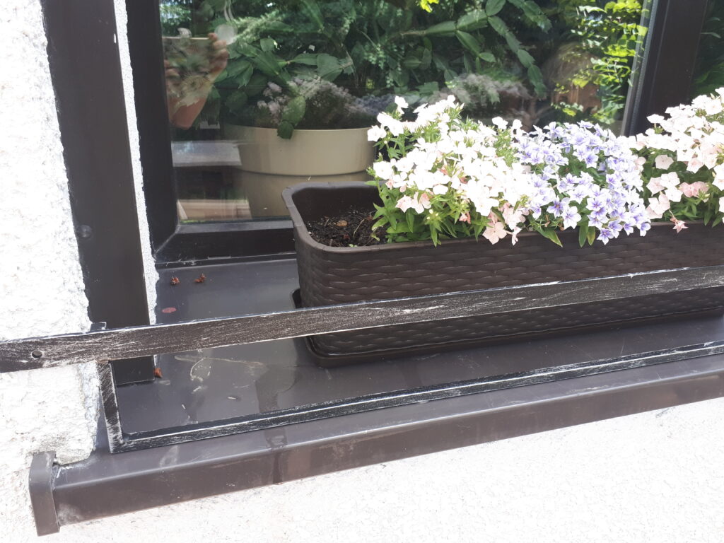 Solidna barierka i minimalistyczny kwietnik na parapet.