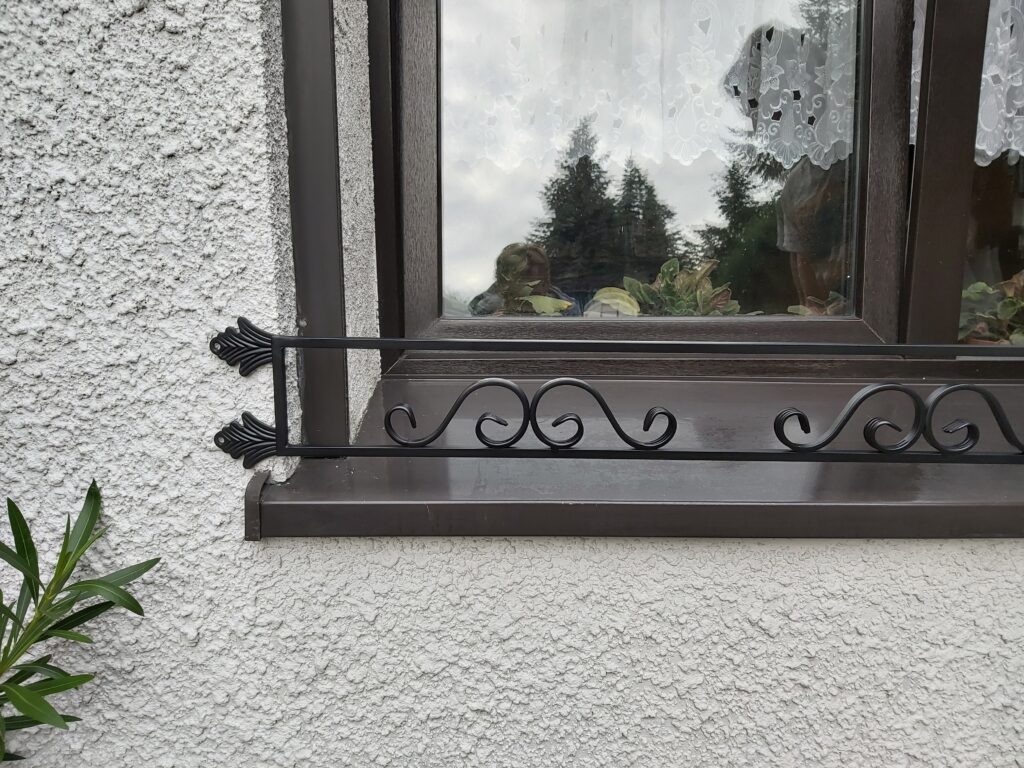 Dekoracyjny kwietnik na zewnątrz okna, idealny do ogrodów miejskich.