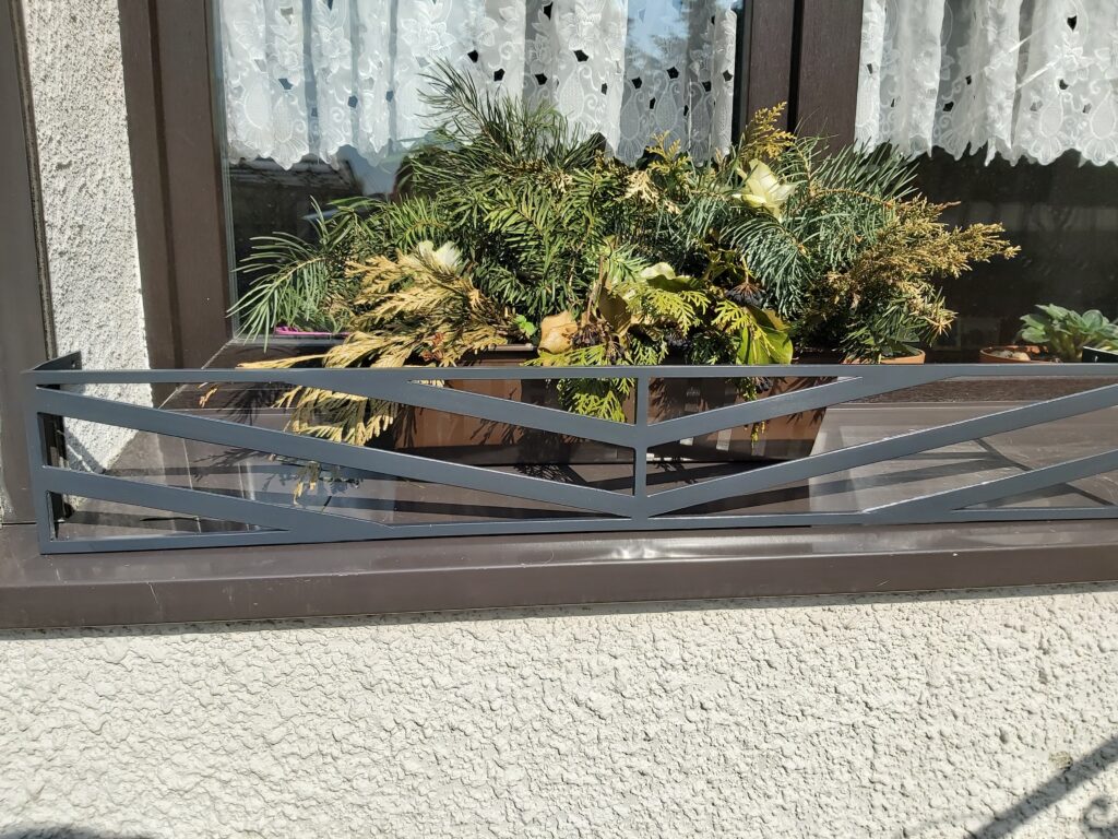 Solidna metalowa barierka z płaskowników atestowanej stali i elegancki kwietnik na parapet - solidność i nowoczesny design.