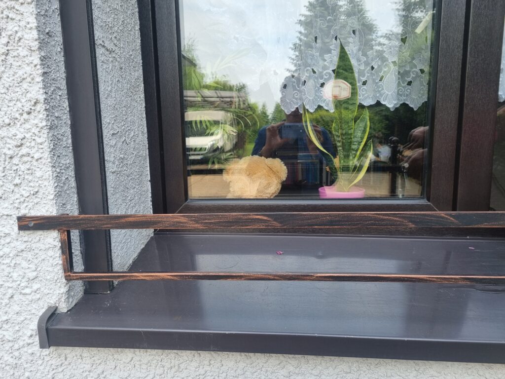 Solidna barierka i minimalistyczny kwietnik na parapet zewnętrzny.