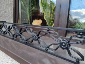 Solidna metalowa barierka z bogatymi ornamentami - eleganckie i wytrzymałe zabezpieczenie dla Twojego parapetu.
