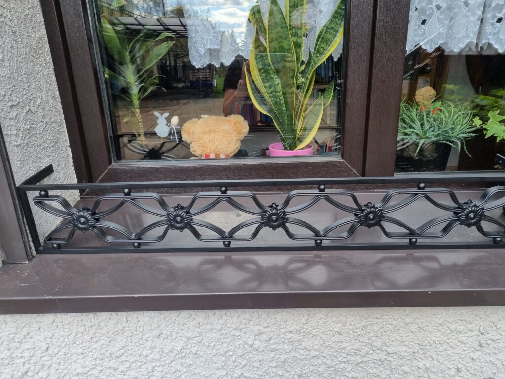 Solidna metalowa barierka z bogatymi ornamentami - elegancja i bezpieczeństwo w jednym.