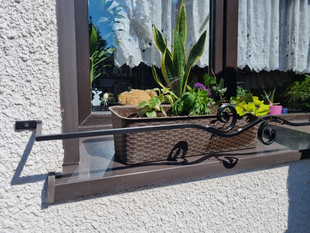 Solidna metalowa barierka z minimalistycznym kwietnikiem na parapet - styl i funkcjonalność.