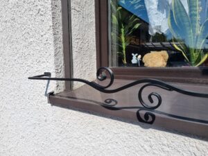 Solidna metalowa barierka z minimalistycznym kwietnikiem na parapet - harmonijne i funkcjonalne.