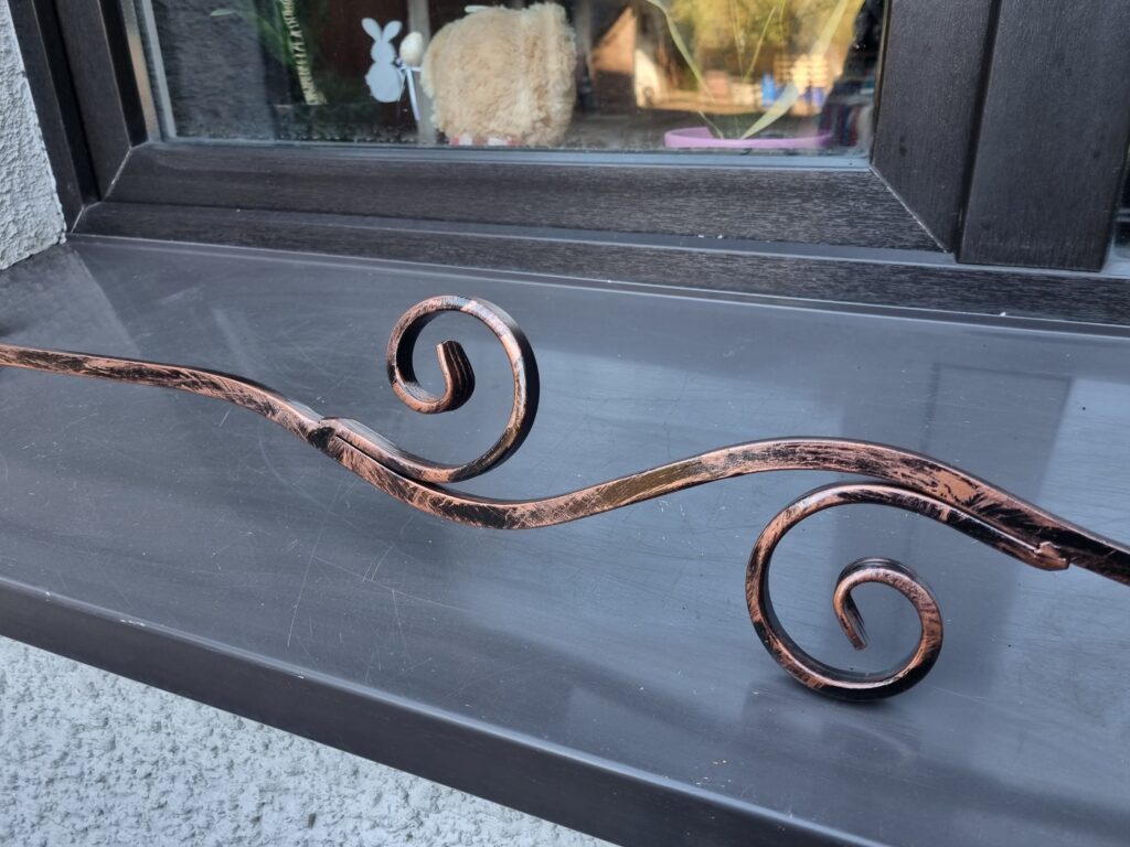 Solidna metalowa barierka z patyną w miedzi i minimalistycznym kwietnikiem na parapet - elegancja i trwałość.