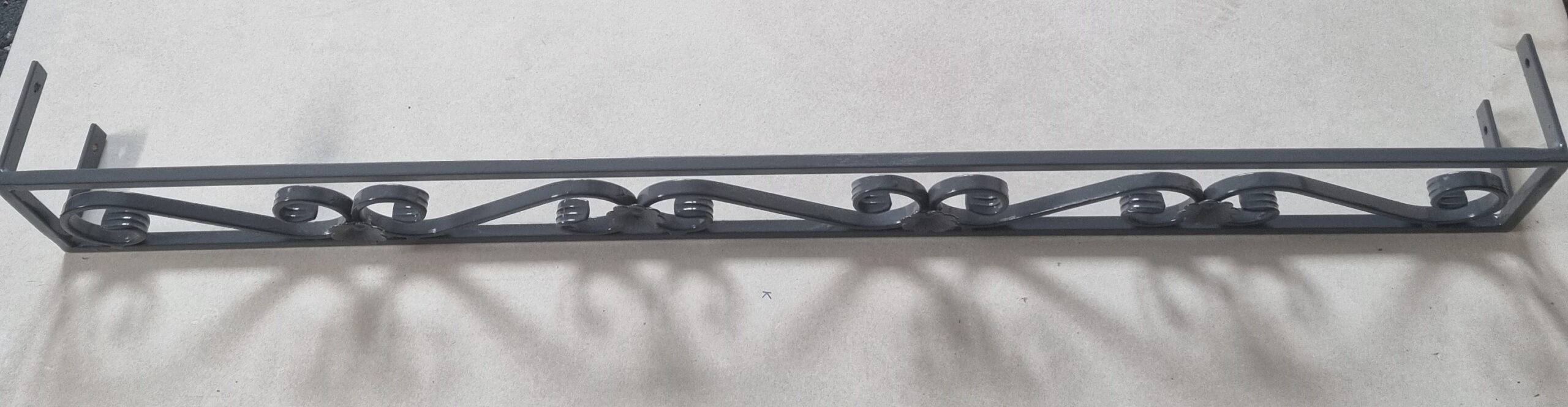 Solidna metalowa barierka z eleganckim wzorem roślinnym kwietnika na parapet - harmonia estetyki i funkcjonalności.