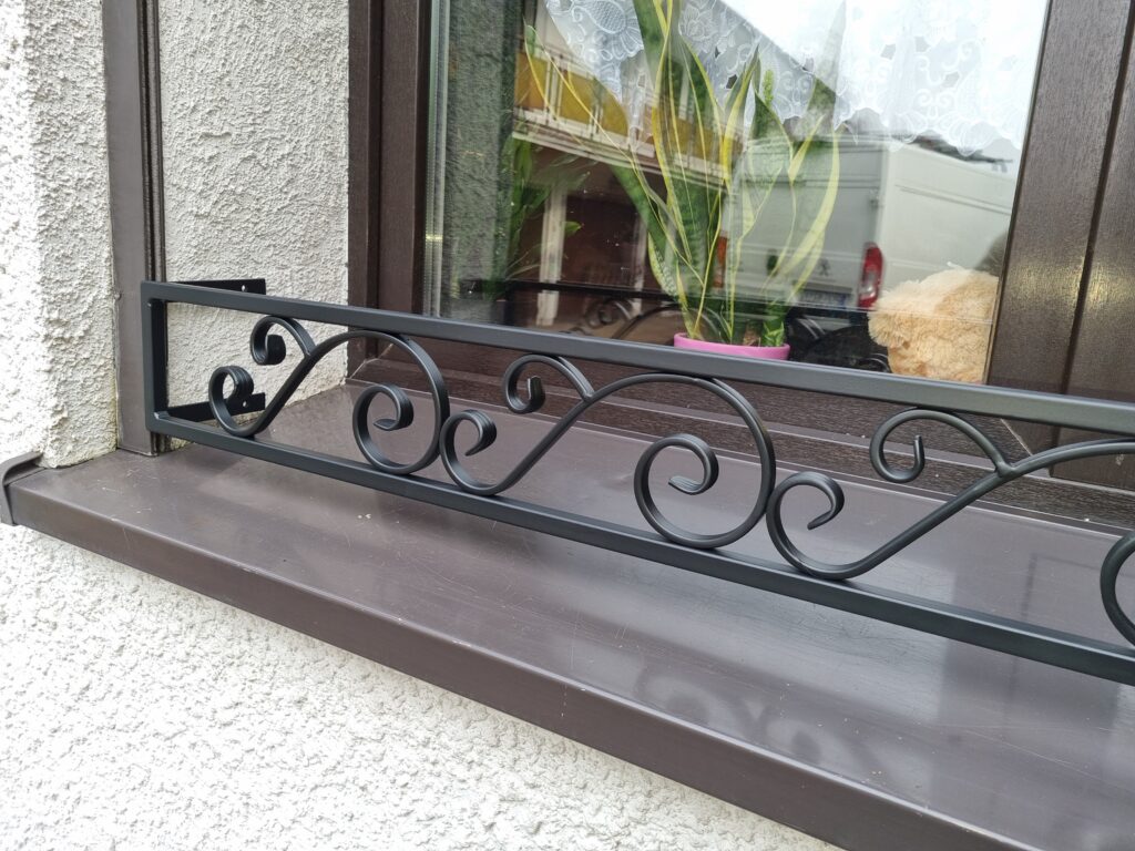 Solidna metalowa barierka z pięknym ornamentem na parapet zewnętrzny - elegancja i trwałość.