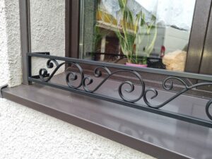 Solidna metalowa barierka z pięknym ornamentem na parapet zewnętrzny - elegancja i trwałość.