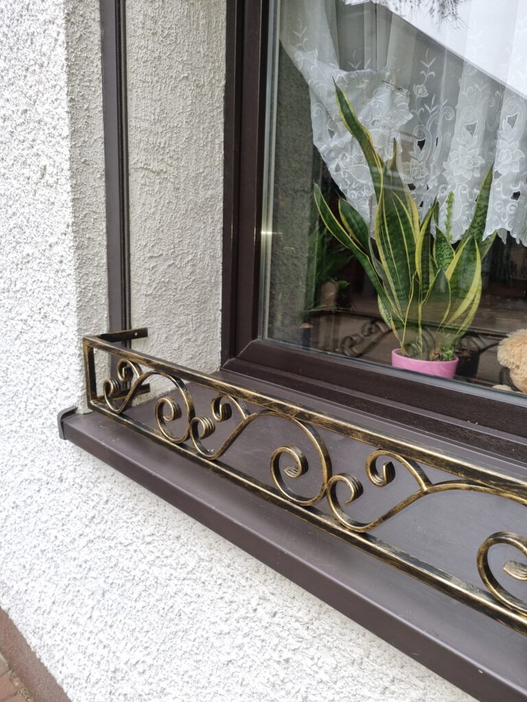 Solidna metalowa barierka z pięknym ornamentem na parapet zewnętrzny - elegancja i trwałość.
