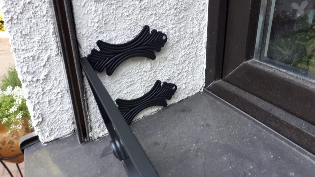 Elegancki metalowy kwietnik na zewnętrzny parapet do skrzynek z kwiatami.