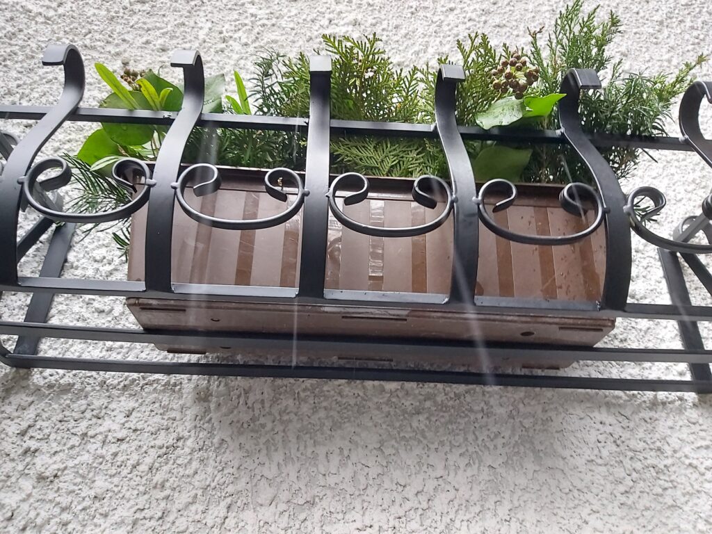 Stylowy metalowy kwietnik-kosz do zamontowania na ścianie lub parapecie.