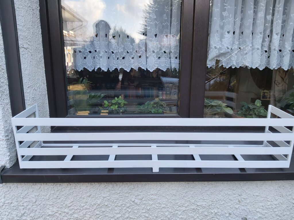 Estetyczny kwietnik na zewnątrz parapetu - funkcjonalna dekoracja zewnętrzna.