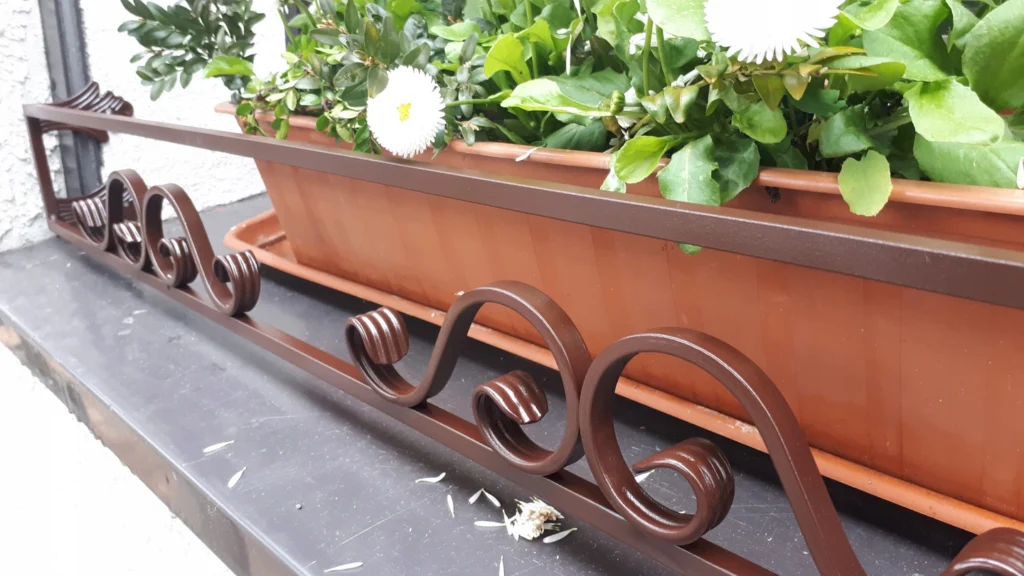 Stylowy kwietnik na parapet zewnętrzny - ozdobna ochrona dla roślin.