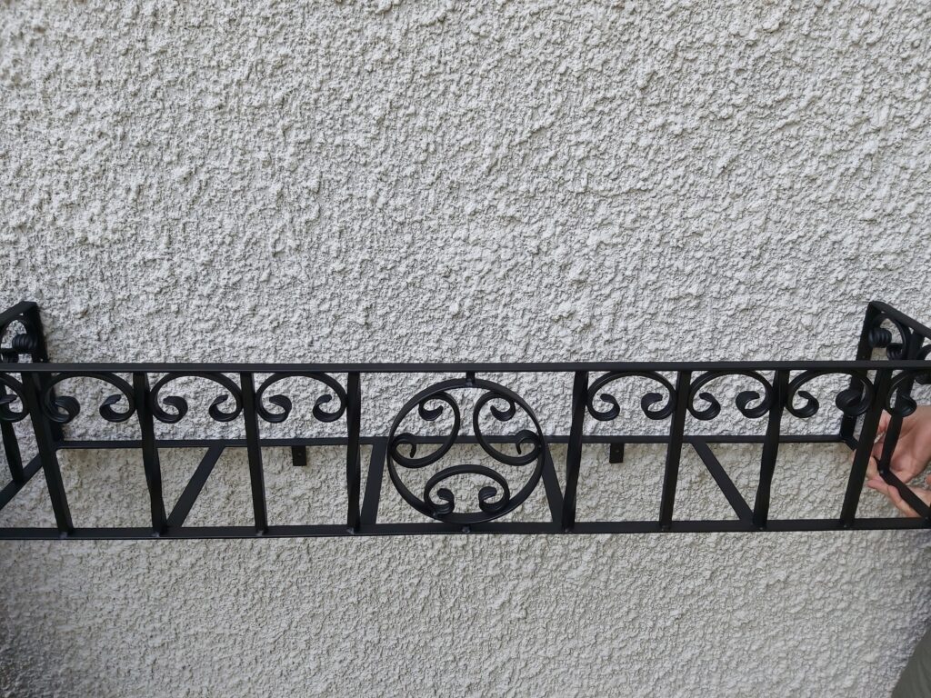 Ręcznie wyginany metalowy kwietnik-kosz na skrzynki z roślinami, elegancki i funkcjonalny.