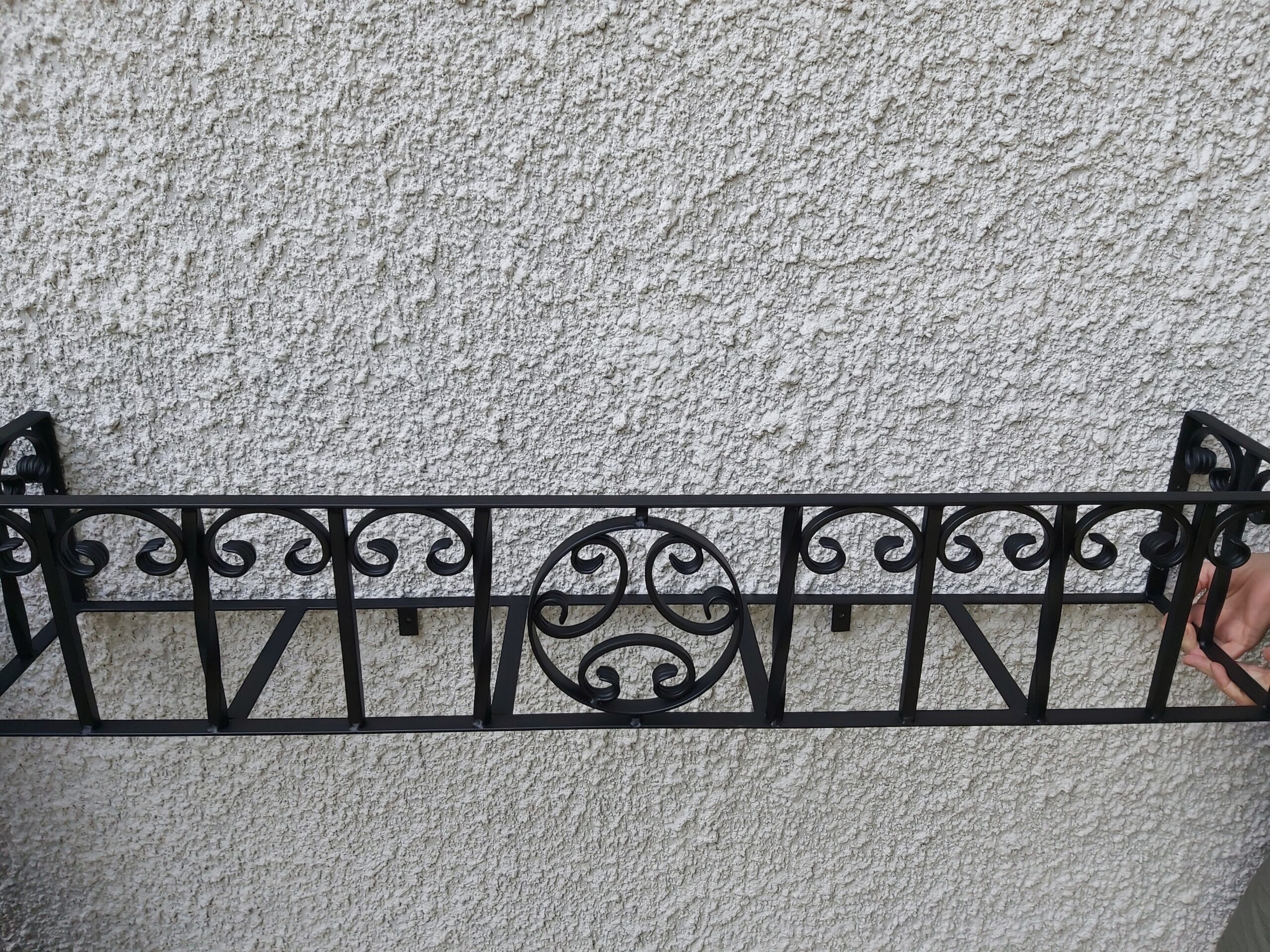Ręcznie wyginany metalowy kwietnik-kosz na skrzynki z roślinami, elegancki i funkcjonalny.