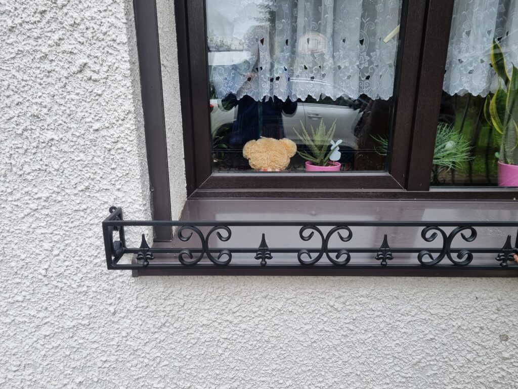 Solidny metalowy kwietnik na parapet zewnętrzny, idealny do ochrony roślin przed wiatrem i deszczem.